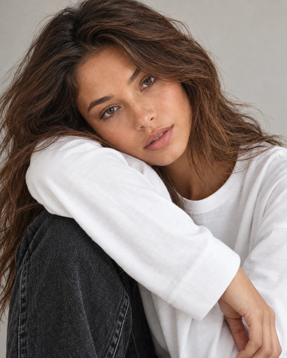 Bliski portret modelki opierającej policzek na rękawie białego longsleeve’u HANNAH.